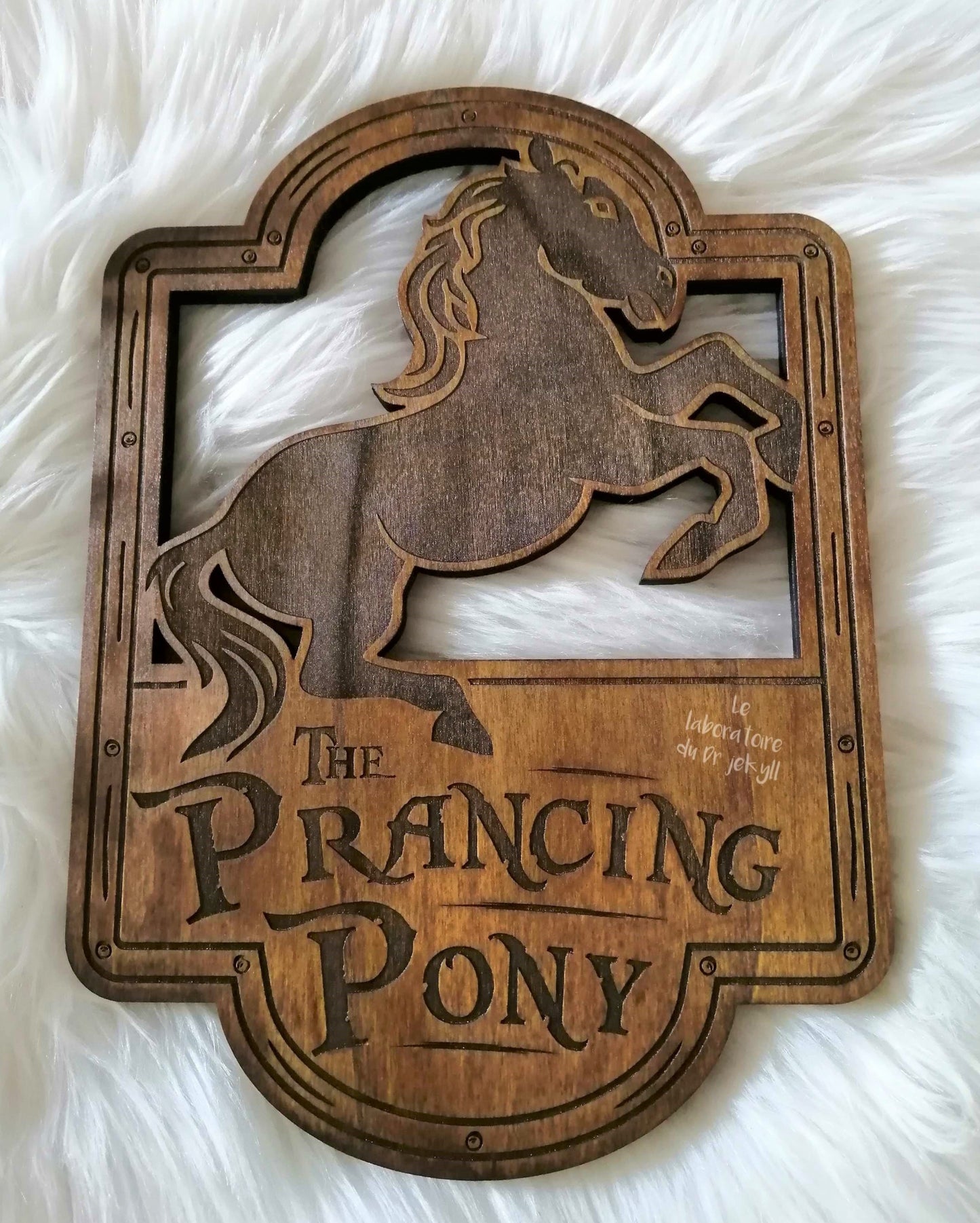 The Prancing Poney, Le Poney Fringant, est une gravure artisanale réalisée sur feuille de peuplier (59 cm x 42 cm ou 33 cm x 23 cm). Chaque pièce est unique en raison des variations naturelles du bois, créant un contraste subtil dans la gravure. Un ajout parfait à votre collection ou pour orner votre pièce de vie. Livré avec son attache murale pour une installation facile. Un objet unique pour les amateurs de décoration originale.