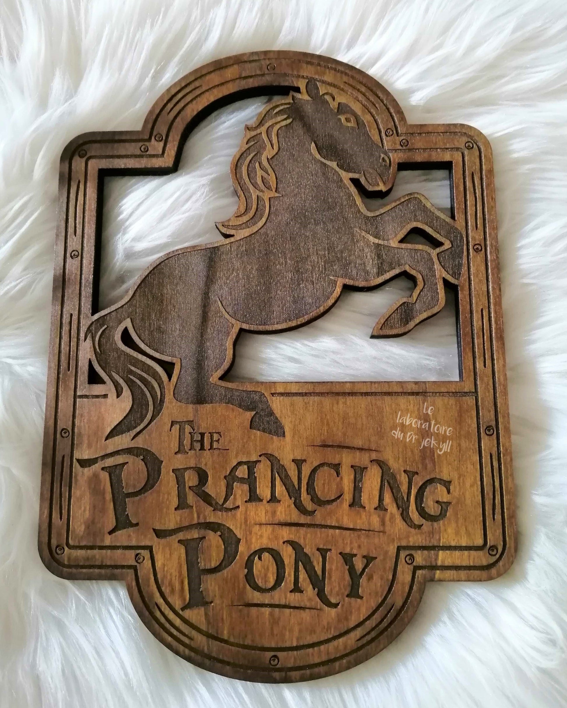 The Prancing Poney, Le Poney Fringant, est une gravure artisanale réalisée sur feuille de peuplier (59 cm x 42 cm ou 33 cm x 23 cm). Chaque pièce est unique en raison des variations naturelles du bois, créant un contraste subtil dans la gravure. Un ajout parfait à votre collection ou pour orner votre pièce de vie. Livré avec son attache murale pour une installation facile. Un objet unique pour les amateurs de décoration originale.
